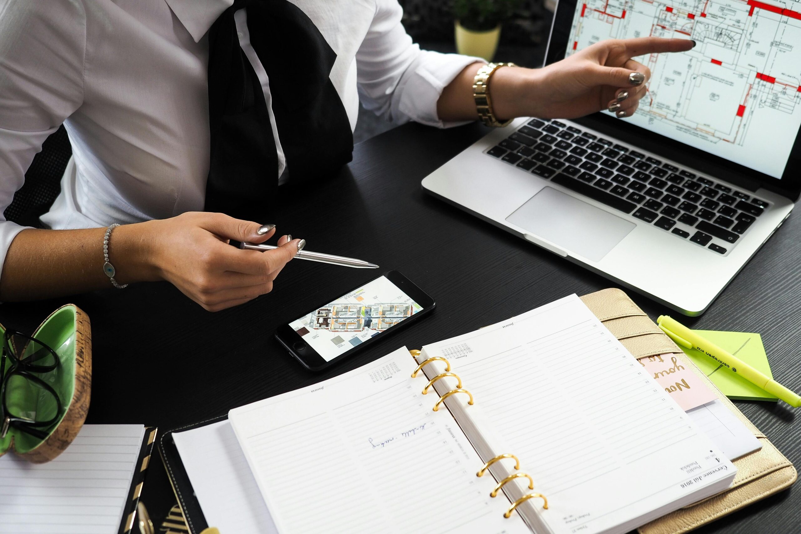 A business professional working on real estate project plans using multiple devices in an office setting.